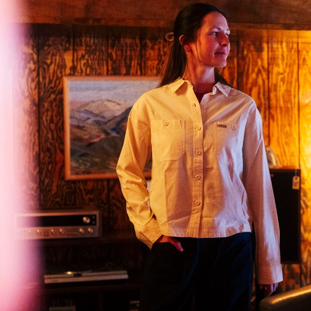 Person standing in a cozy room with warm lighting and artwork on the wall.