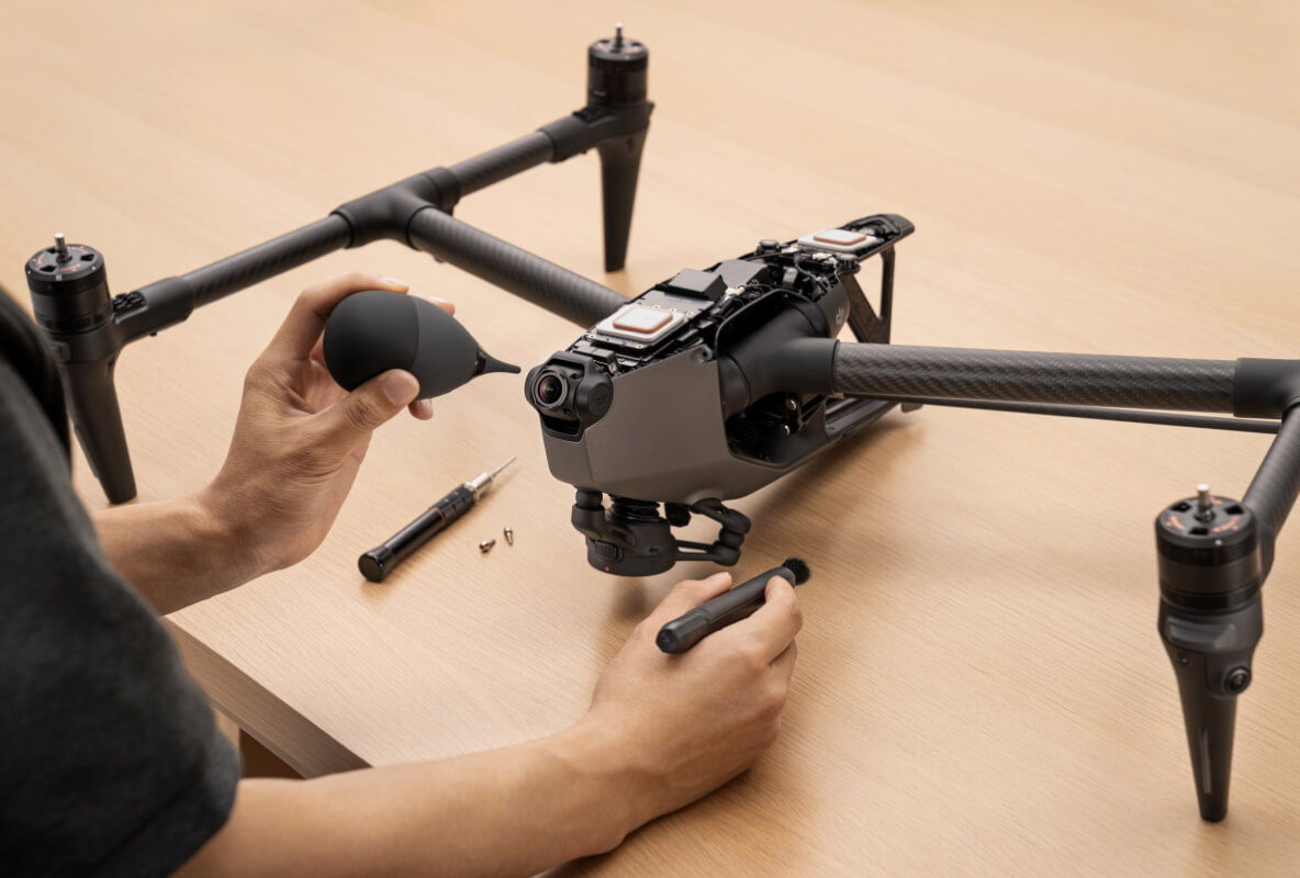 Person completing maintenance on a drone on a wooden table.