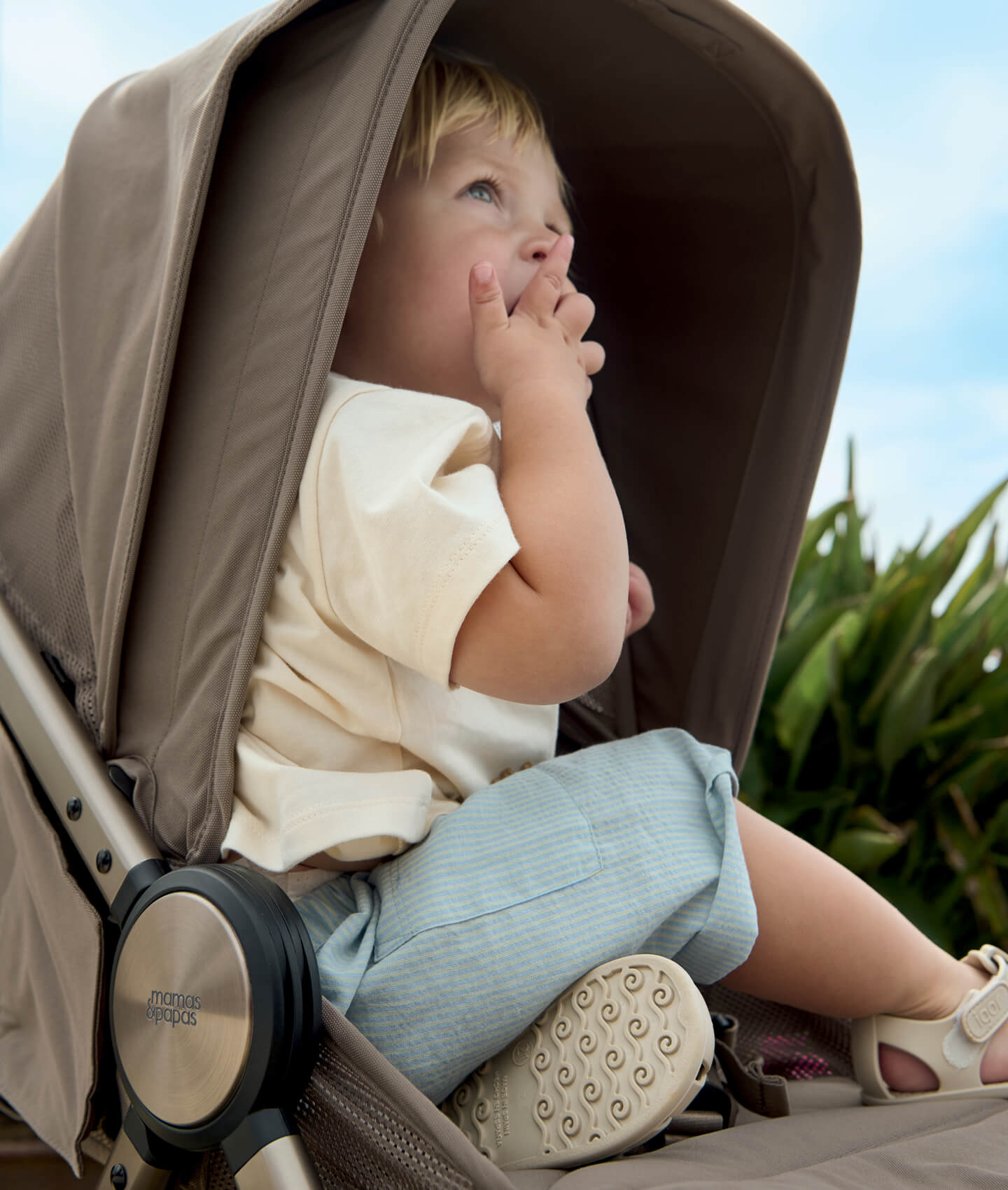 Child sitting in stroller, looking up with a thoughtful expression.