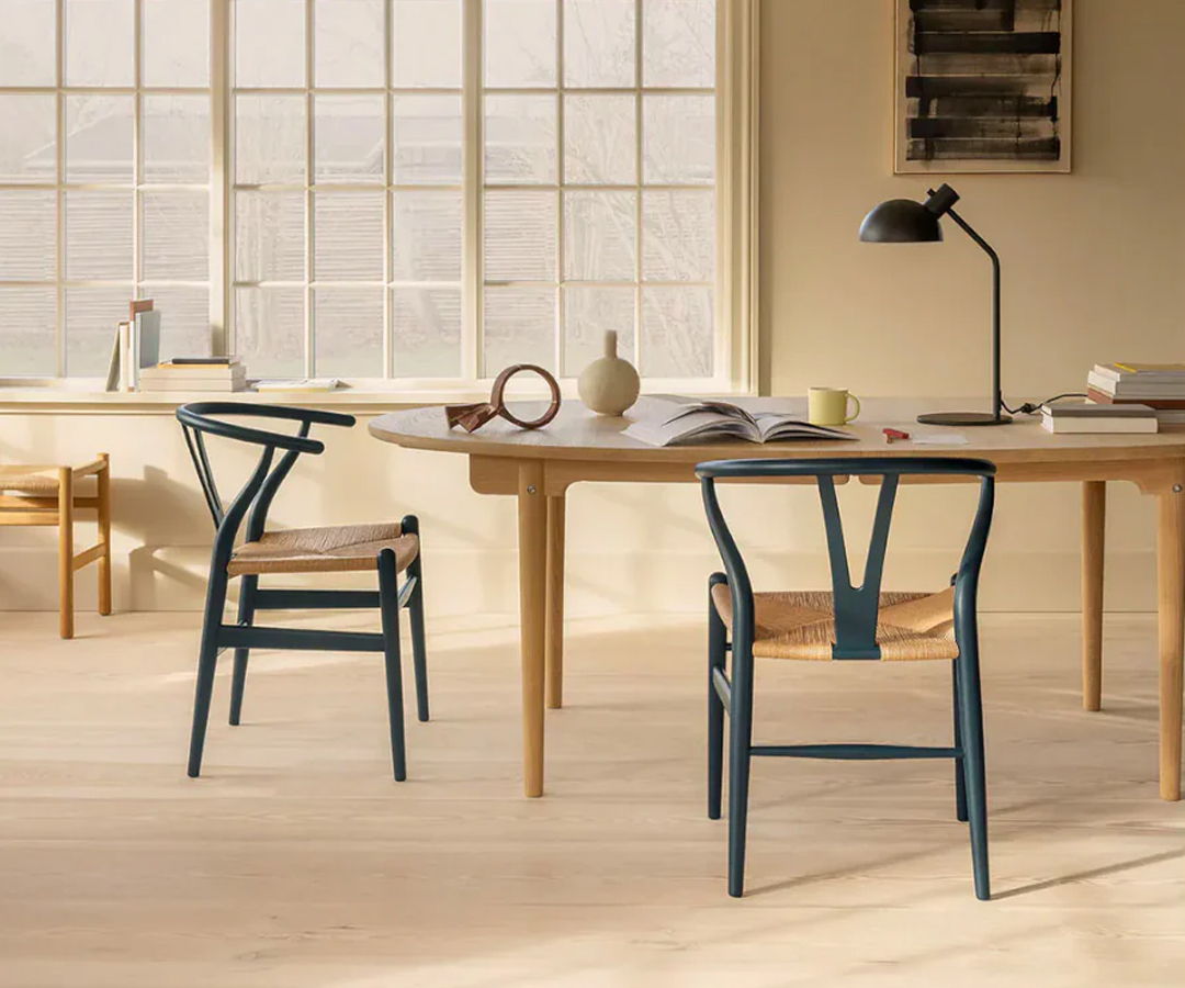 Modern interior with Carl Hansen wooden table, chairs, and natural light from large windows.