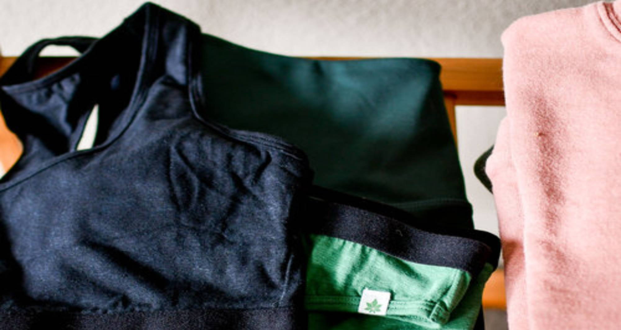 black bralette and green underwear folded on clothing bench