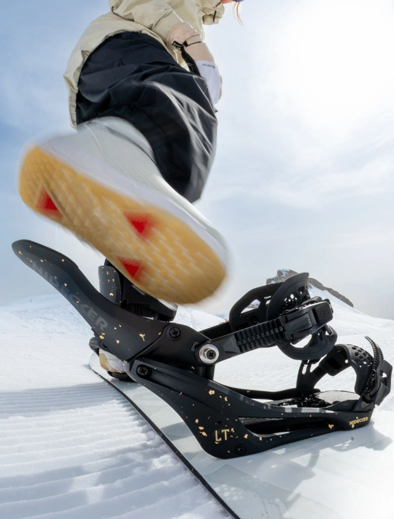 A snowboard binding with a foot about to step onto it.