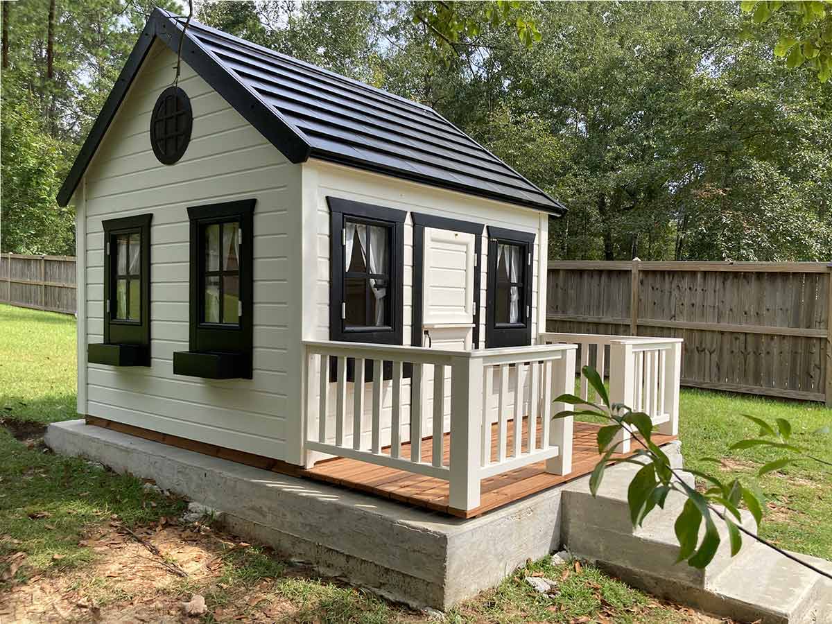 Black and white wooden playhouse with black roof, flower boxes and wooden terrace by WholeWoodPlayhouses
