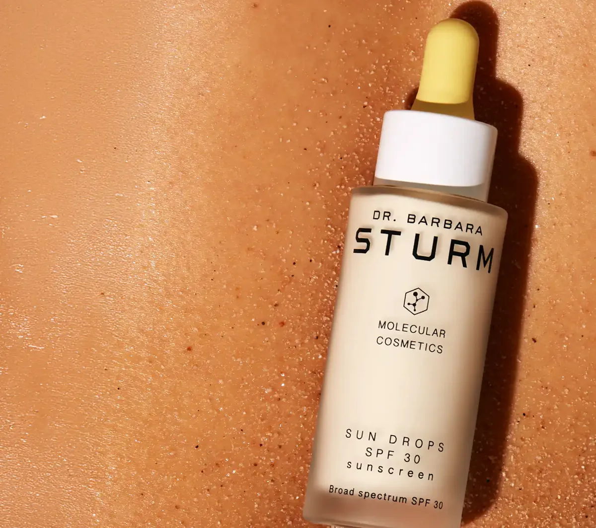 Bottle of Dr. Barbara Sturm sun drops on a beige background.