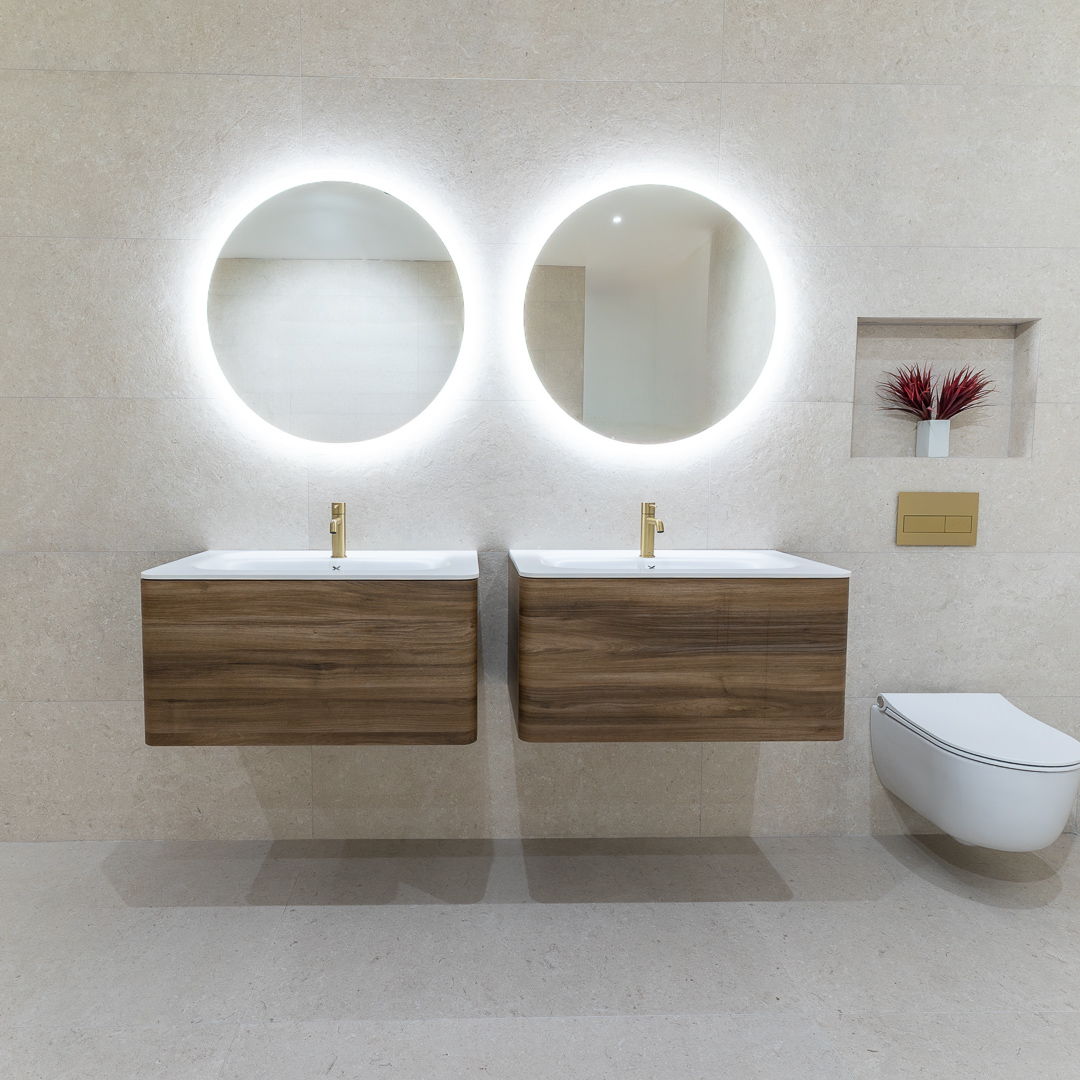 Modern bathroom with two sinks, circular mirrors, and a toilet.
