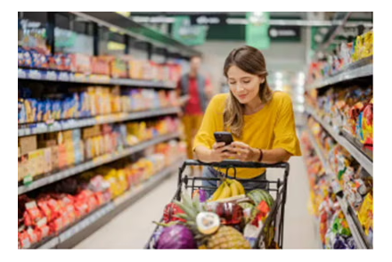 Woman shopping in a grocery store, looking at her phone.