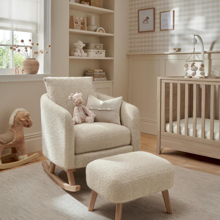 Cozy nursery with rocking chair, ottoman, and crib. Soft pastel decor.