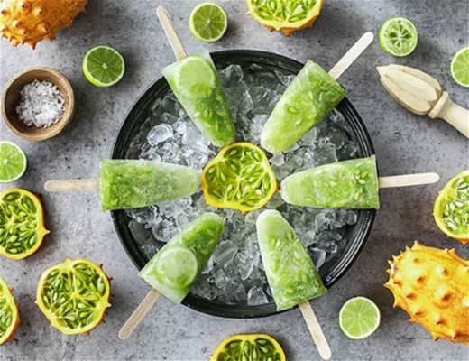 Green popsicles surrounded by fruit and ice in a circular arrangement.
