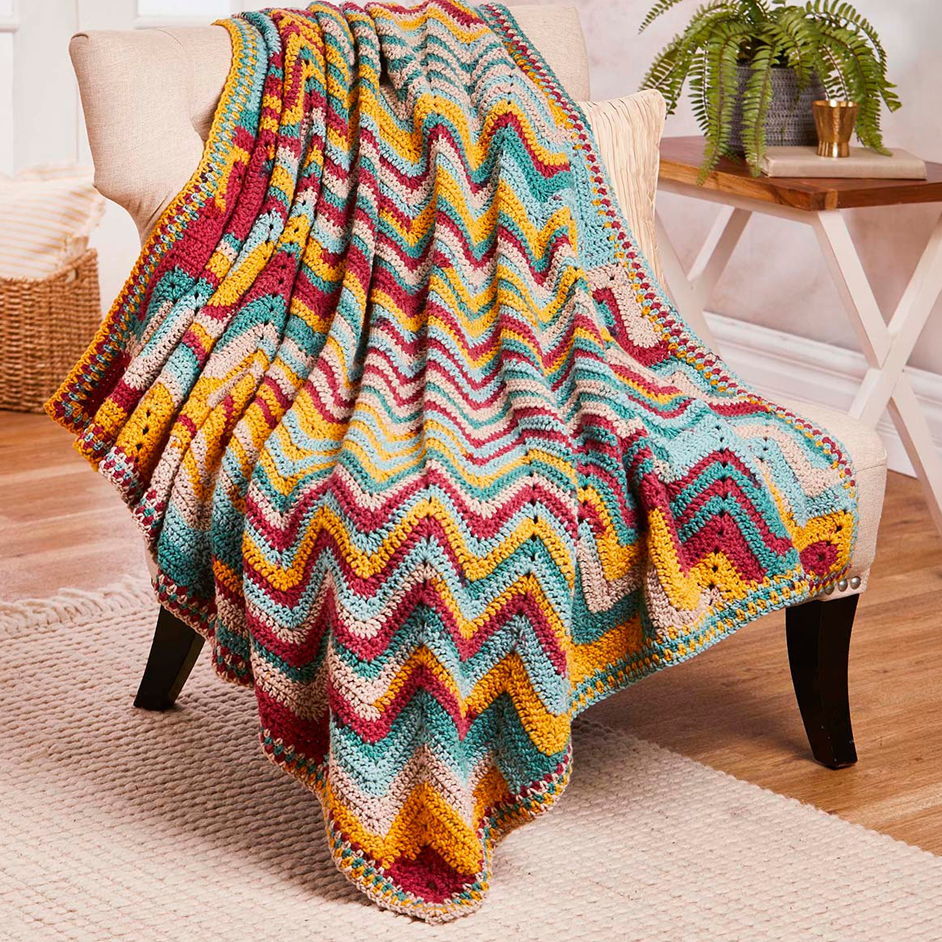 Colorful zigzag patterned blanket draped over a chair in a cozy room.