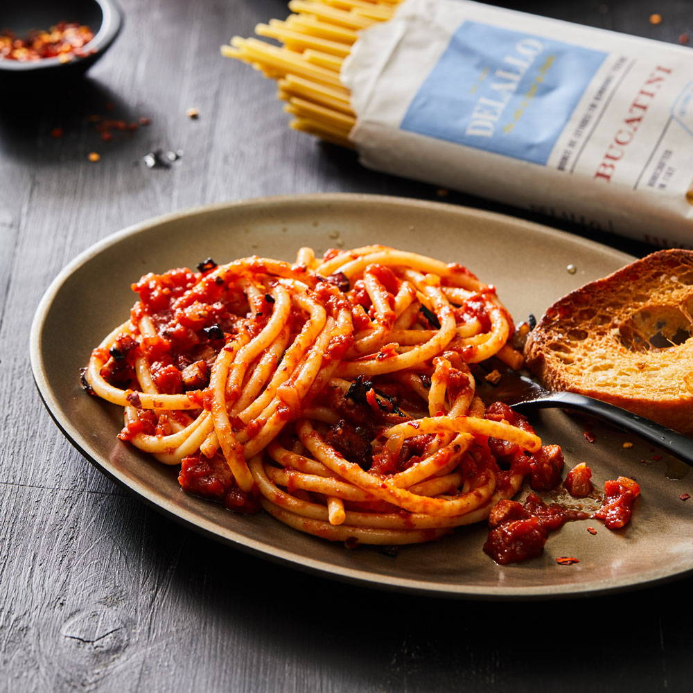 Bucatini pasta on a plate tossed in a red sauce