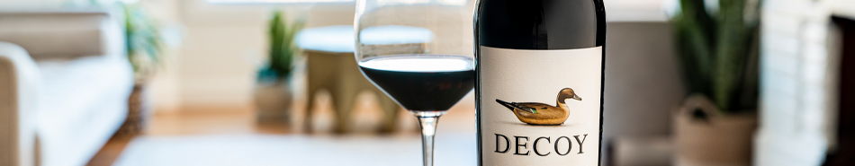 A bottle of Decoy wine beside a glass of red wine.