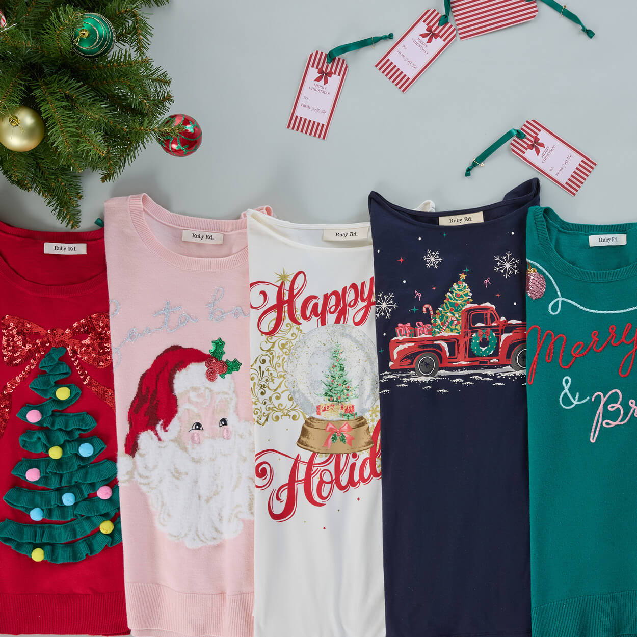 Five holiday-themed shirts with tags and a decorative tree.
