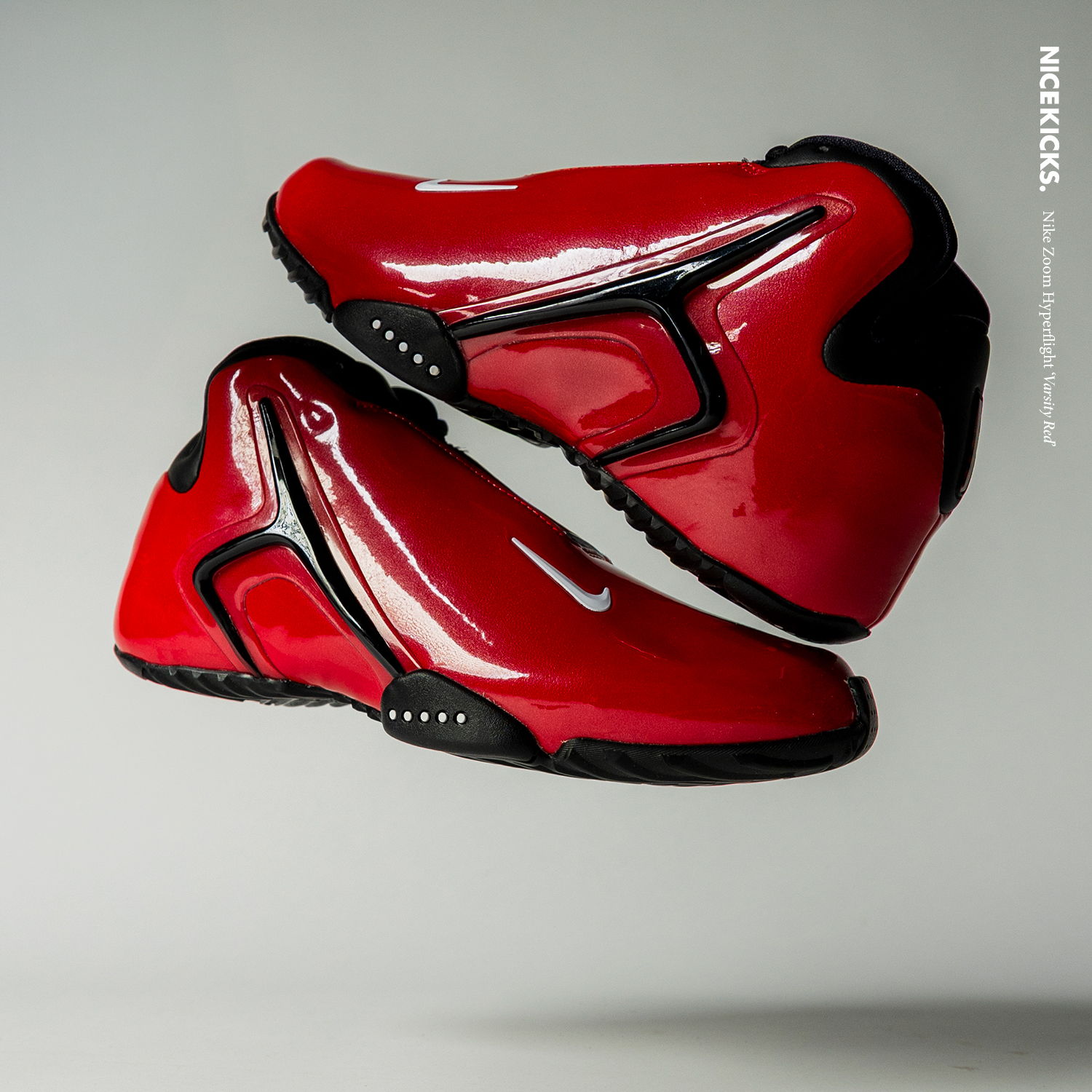A pair of red and black athletic shoes floating against a neutral background.