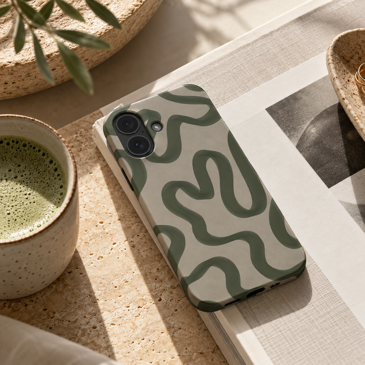 Beige phone case with green swirling lines on a desk 