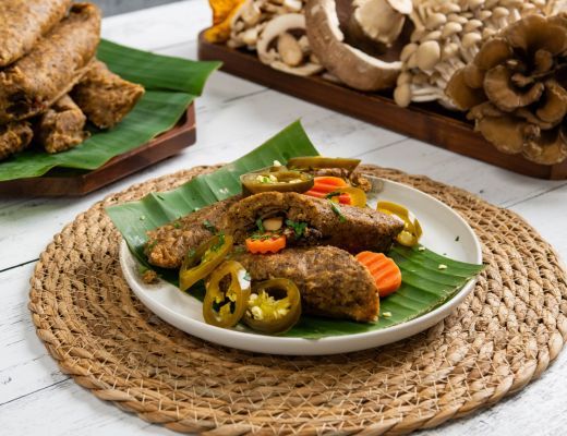 Plate of food with vegetables on a banana leaf, surrounded by mushrooms.
