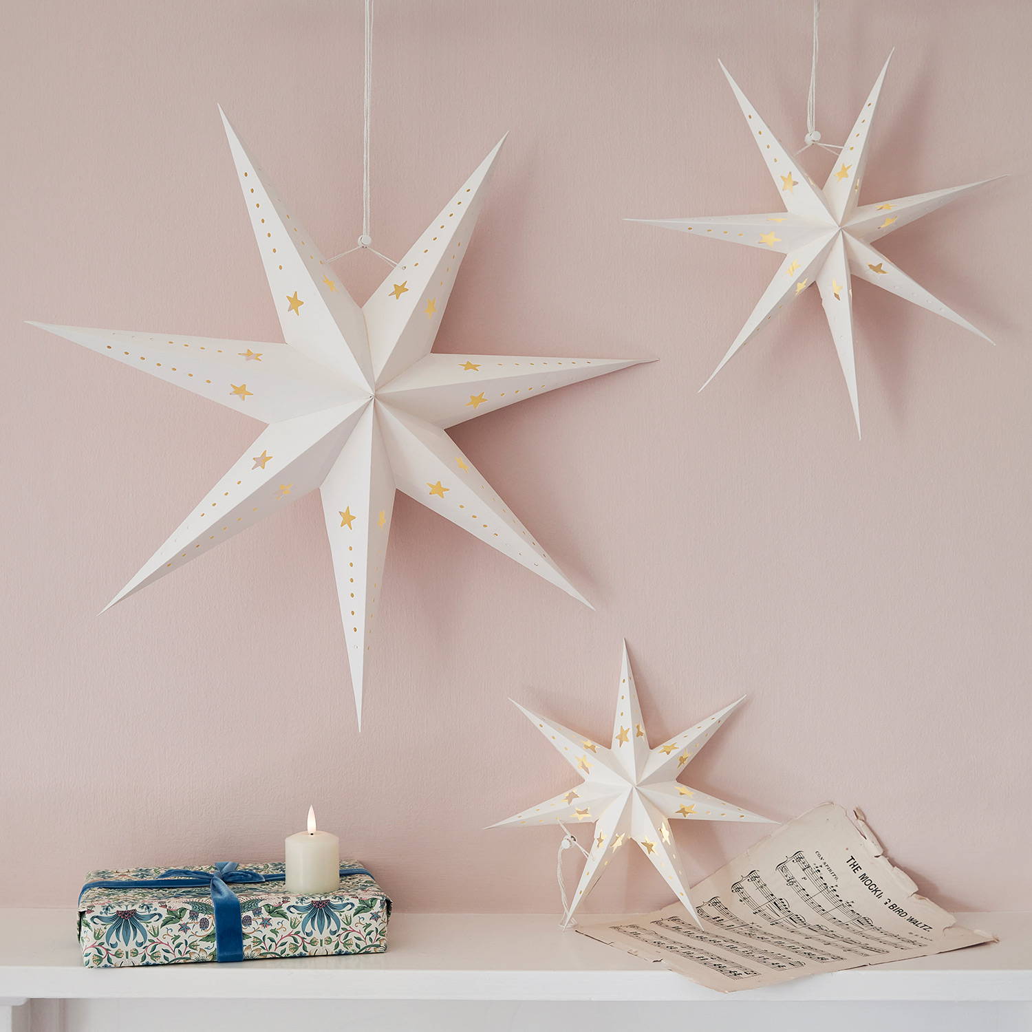 3 paper star decorations hanging over a mantlepiece