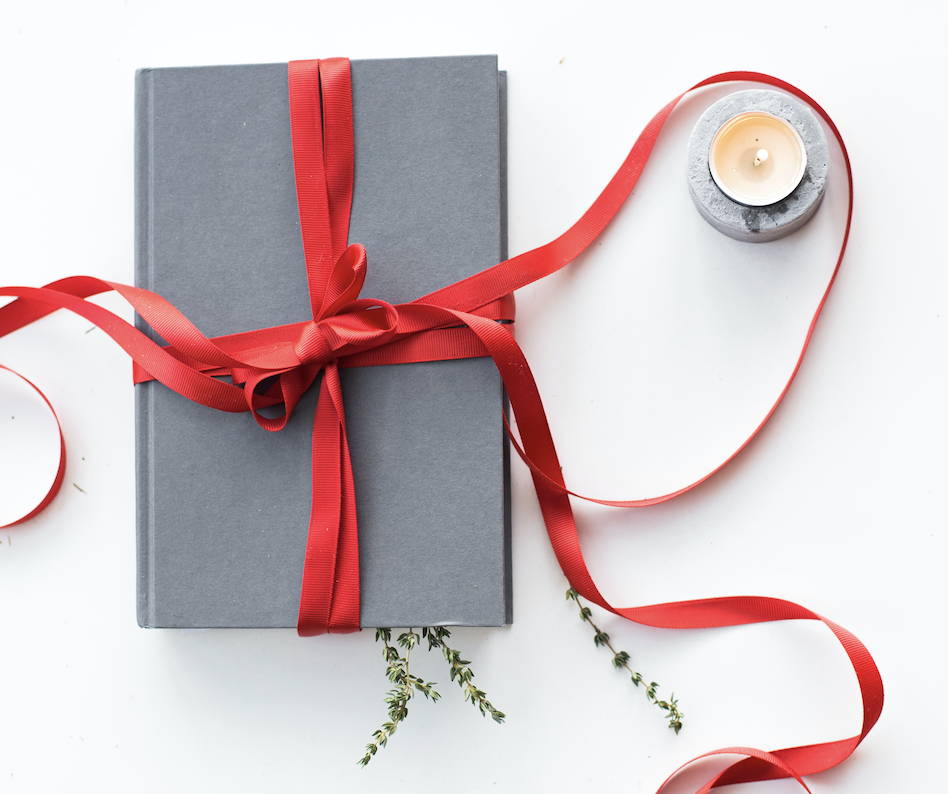 Planner on a table with a holiday ribbon tied around it. Candle situated in the corner.