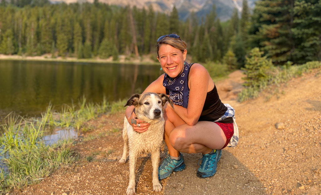 Portrait of Lauren Berutich and her dog Lili next to a lake.