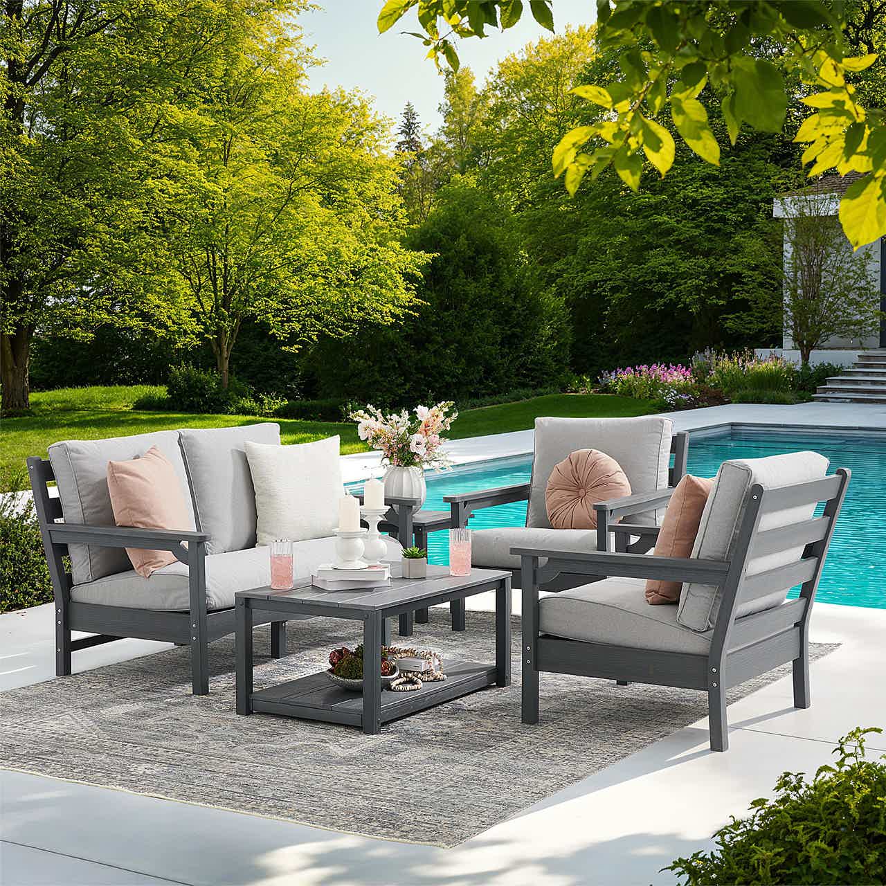 Outdoor seating area by a pool, featuring gray furniture and decorative pillows.