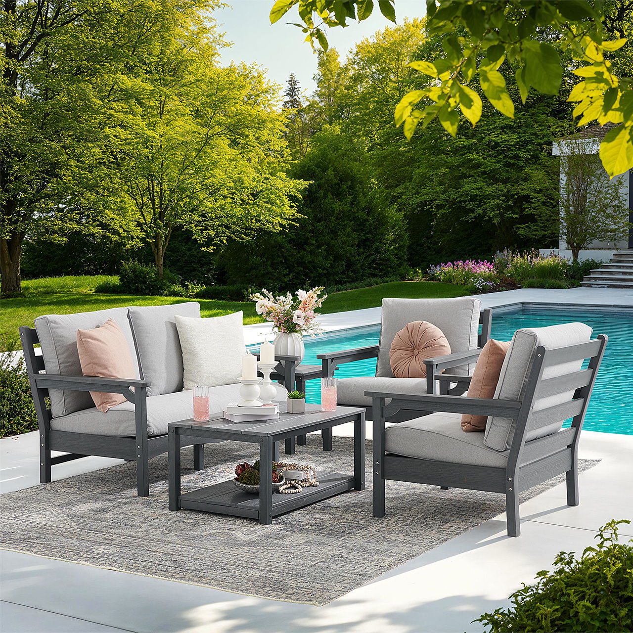 Outdoor seating area by a pool, featuring gray furniture and decorative pillows.