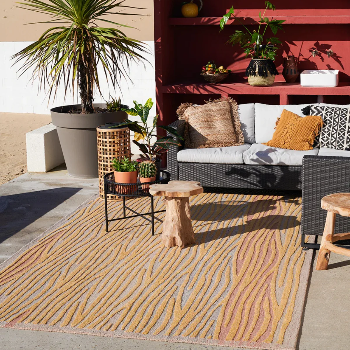 Outdoor patio featuring a colorful performance rug with recycled plastic fibers beneath wicker seating, demonstrating fade-resistant outdoor rugs designed for sunny desert environments. 