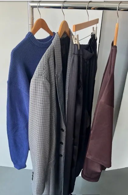 Clothes hanging on a rack, including sweaters and pants.