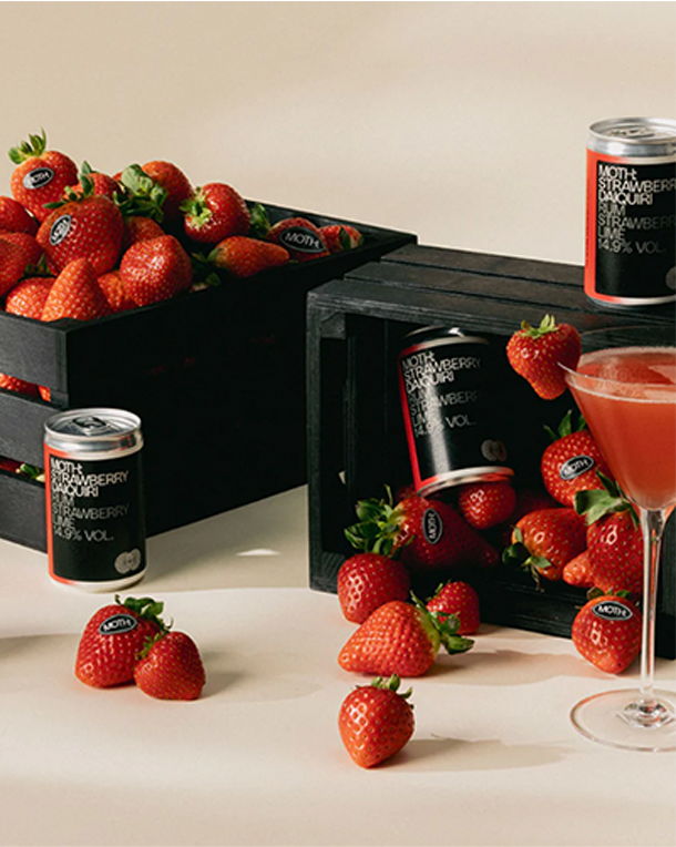 Strawberries, cans, and a cocktail glass on a neutral background.