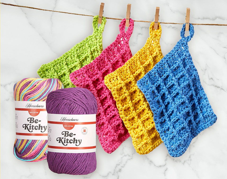Colorful crochet dishcloths hanging with Be- Kitchy yarn skeins on the side.