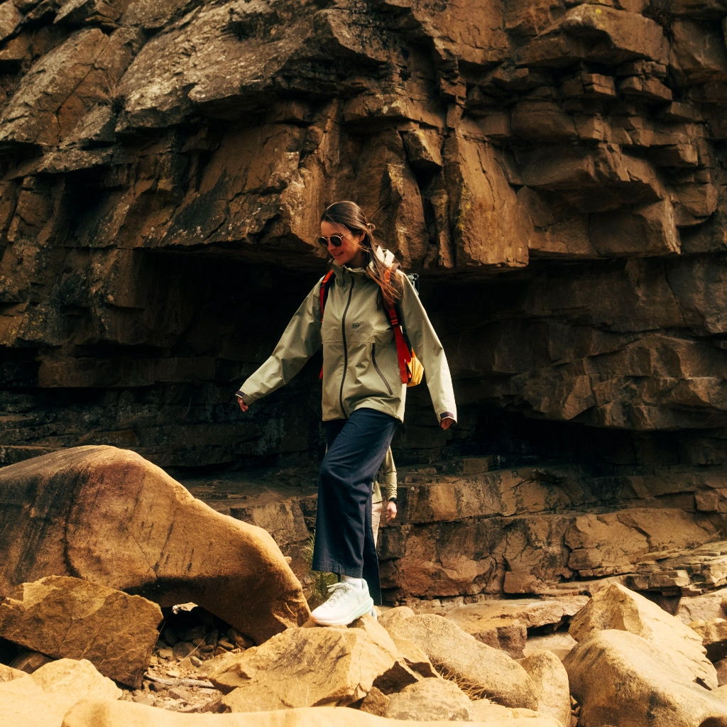 Person hiking on rocky terrain near a cliff.