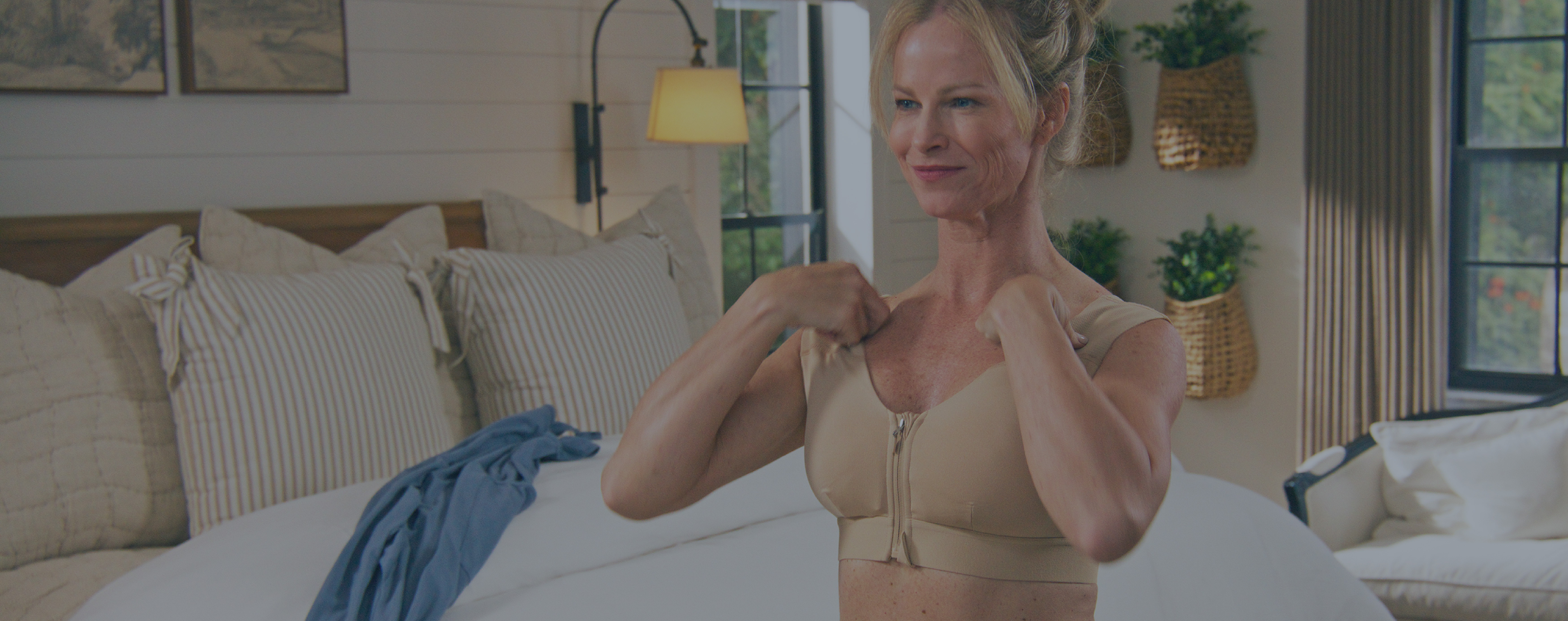 Woman putting on the Zipper Shoulder Support Bra in nude