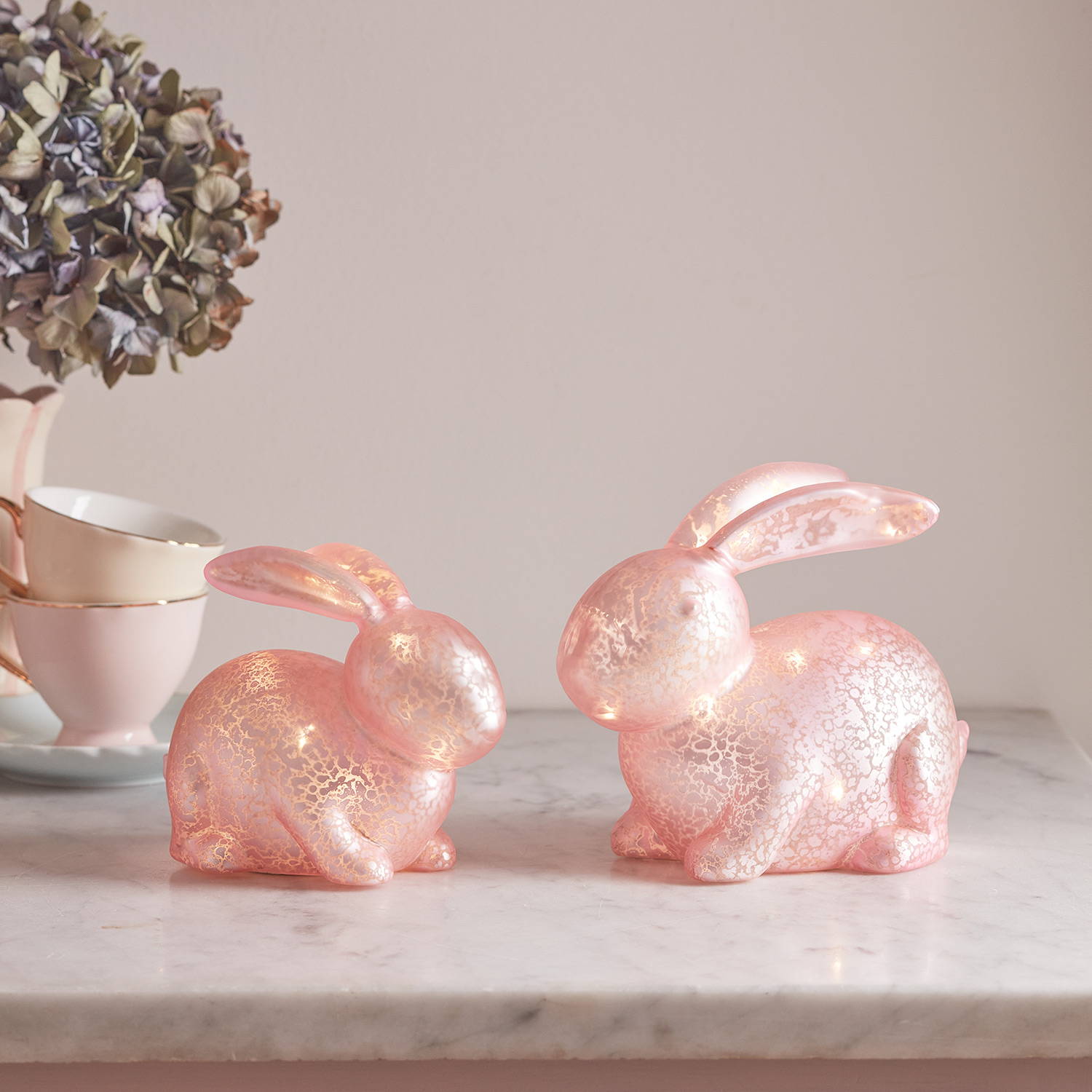 2 Décos de Pâques, Lapins Lumineux Roses en Verre Moucheté sur un comptoir de cuisine.