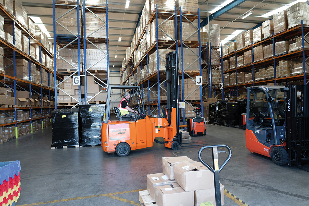 Forklifts operating in a warehouse filled with stacked boxes on shelves.
