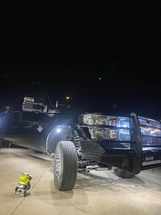 Troy's black 2012 Ford F250 at night with front brush guard and LED rock lights