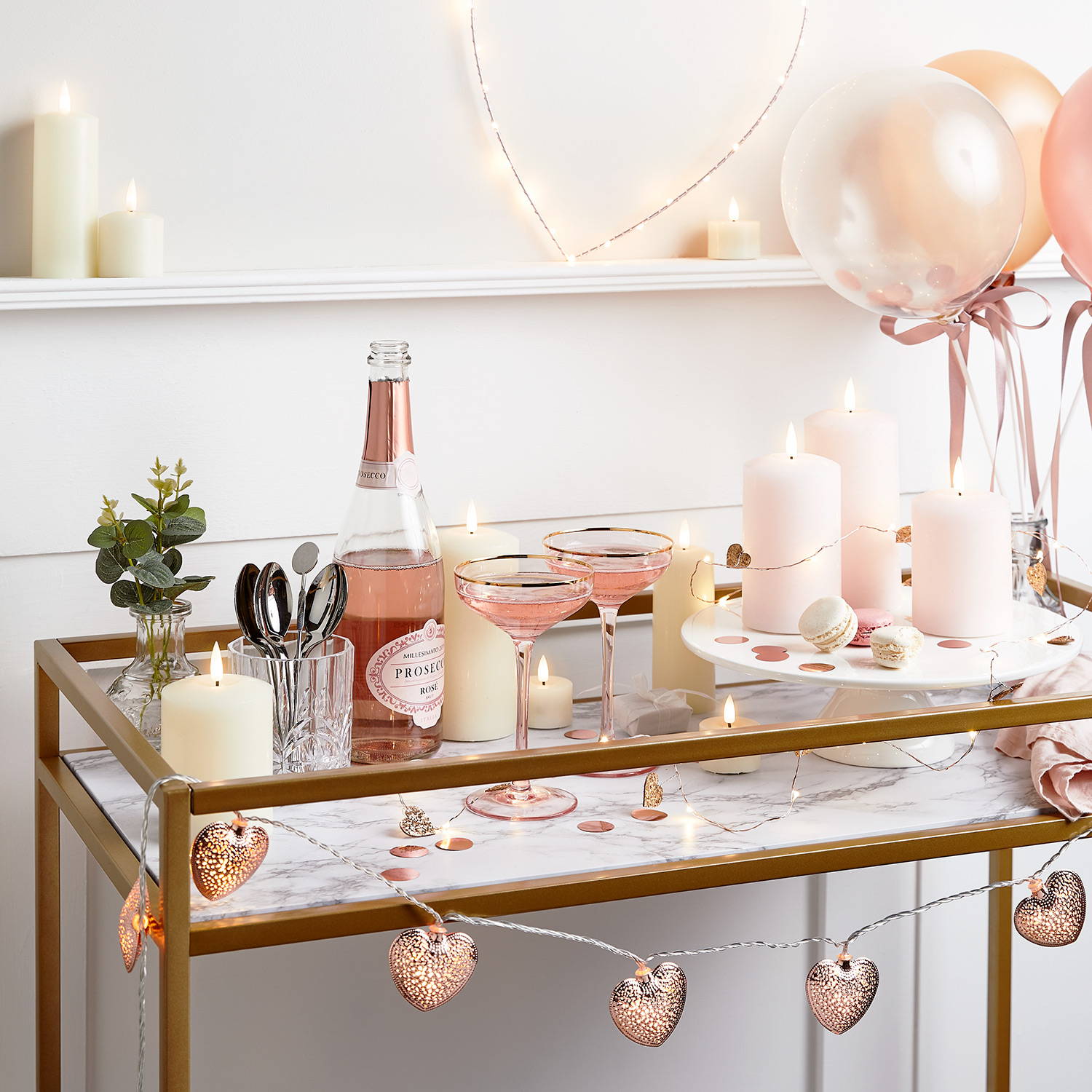 A Valentine's day bar chart with heart fairy lights, cocktail glasses, champagne and candles. 