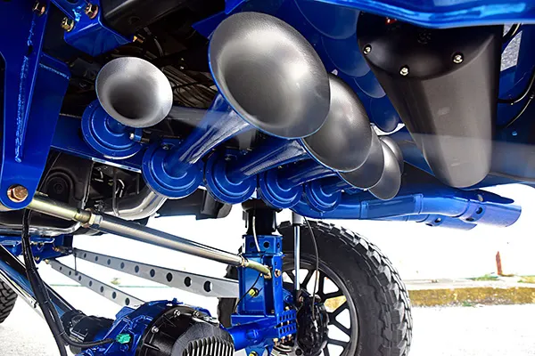 Close-up of five silver train horns and black air tank mounted on Jeff's blue-painted Ford F250 chassis