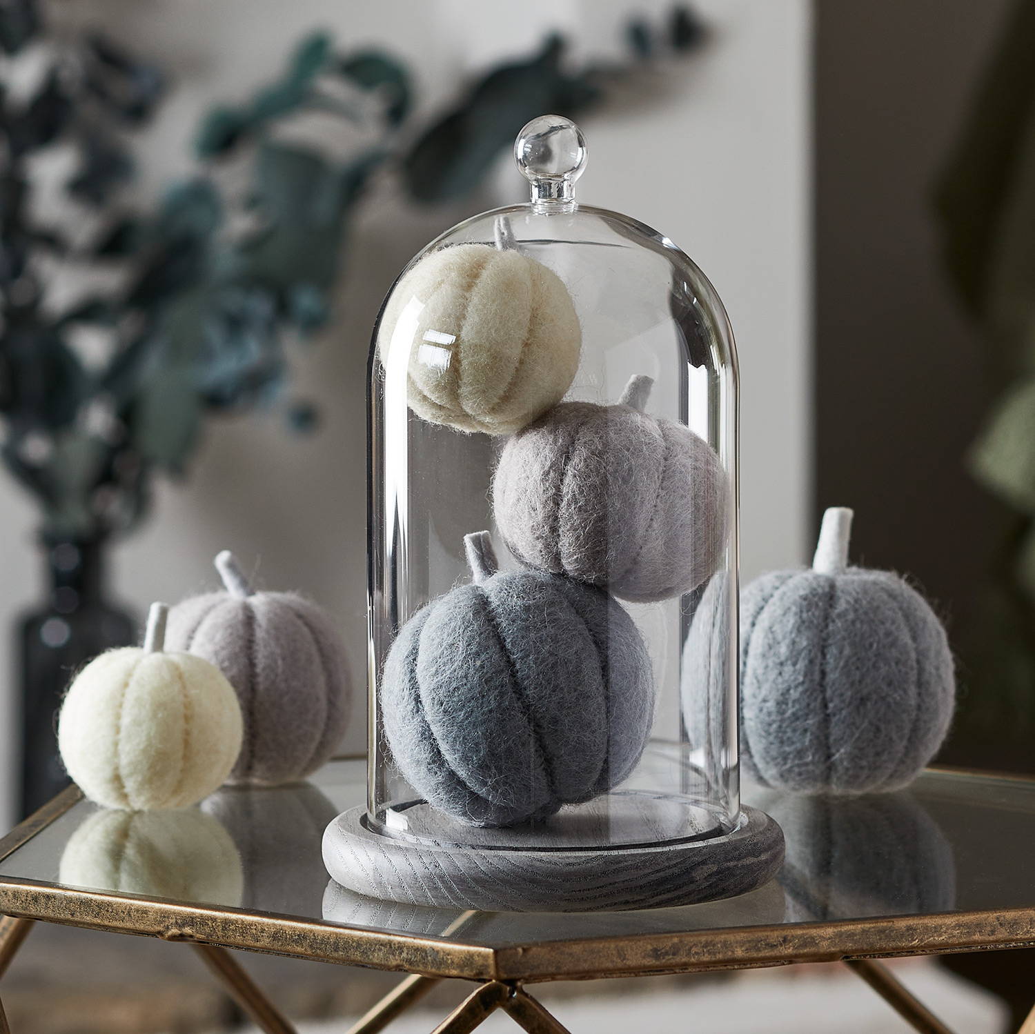 Glass dome stacked with grey felt pumpkins in a living room setting