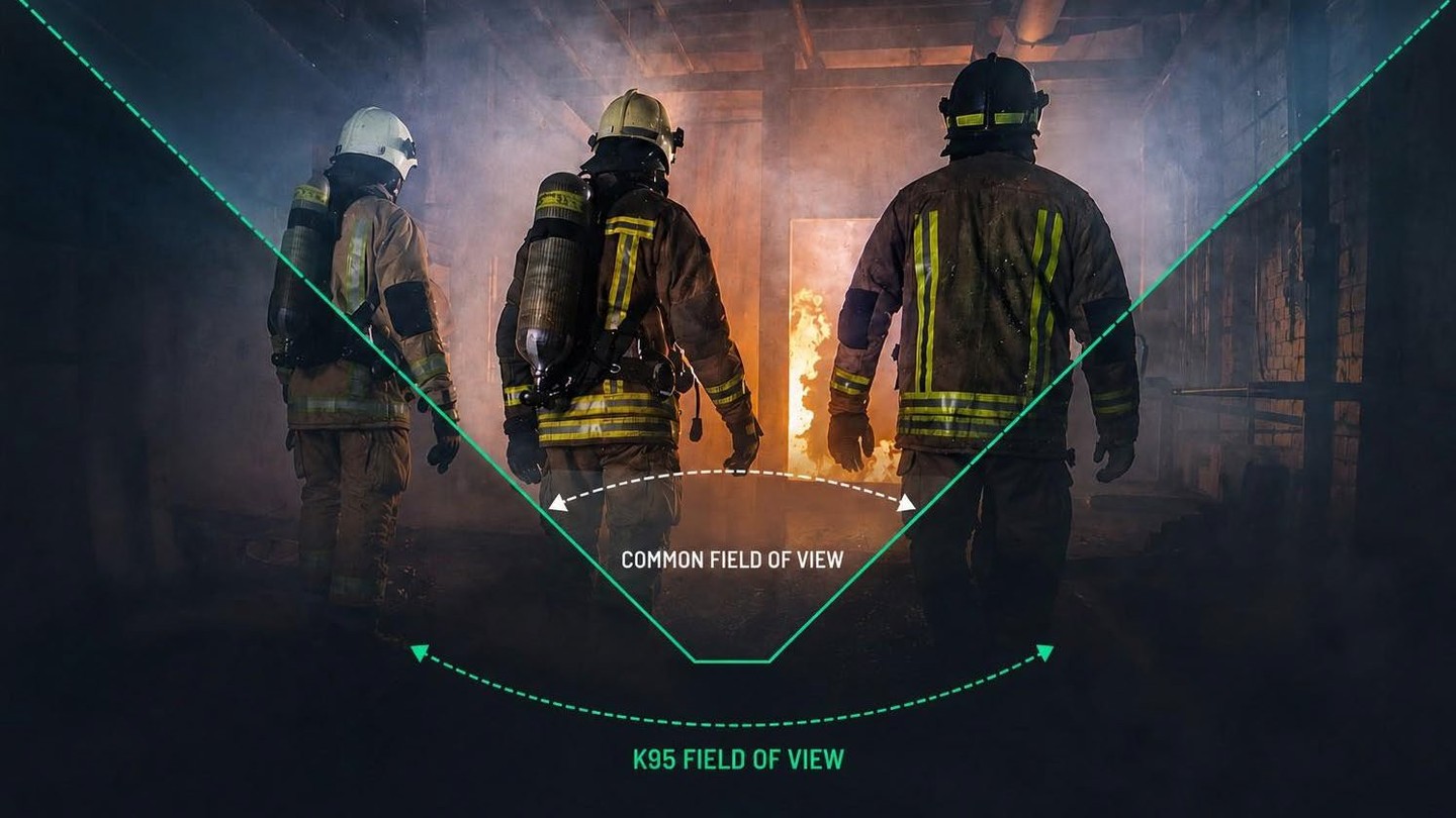 Three firefighters standing together, facing a fire in a dark environment.