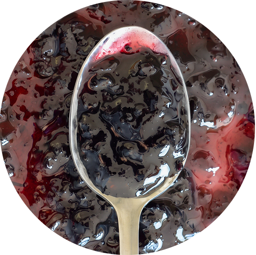 Spoonful of Tastefully Simple Blissful Blueberry Jam showing its thick texture and blueberry pieces.