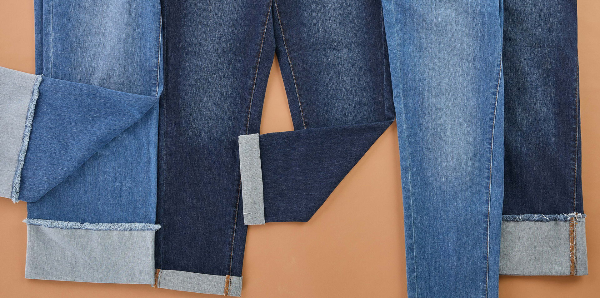 Various pairs of rolled-up jeans on a flat surface.