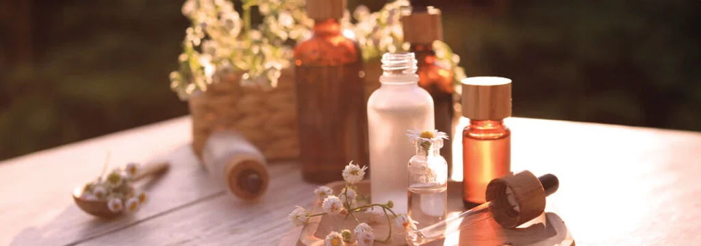 Bottles and flowers arranged on a wooden table in soft lighting.