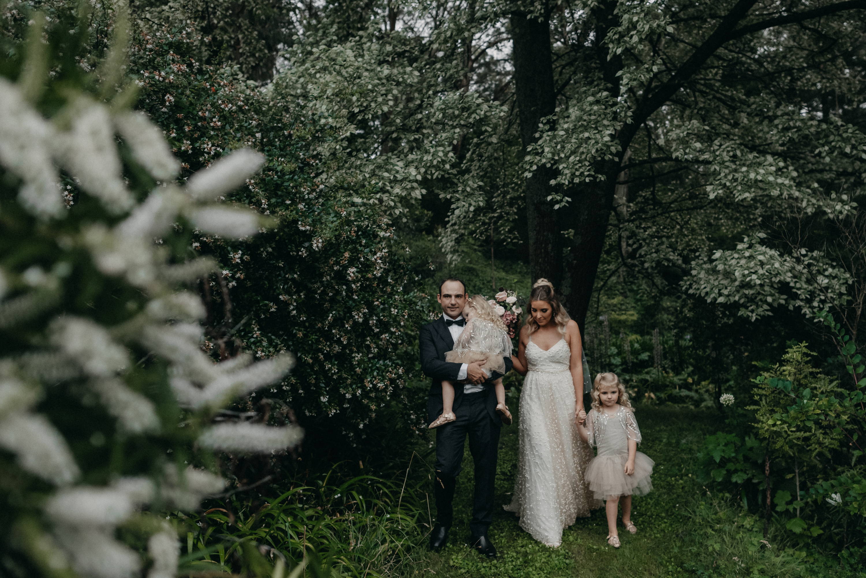 Bride and groom with daughters in garden wedding