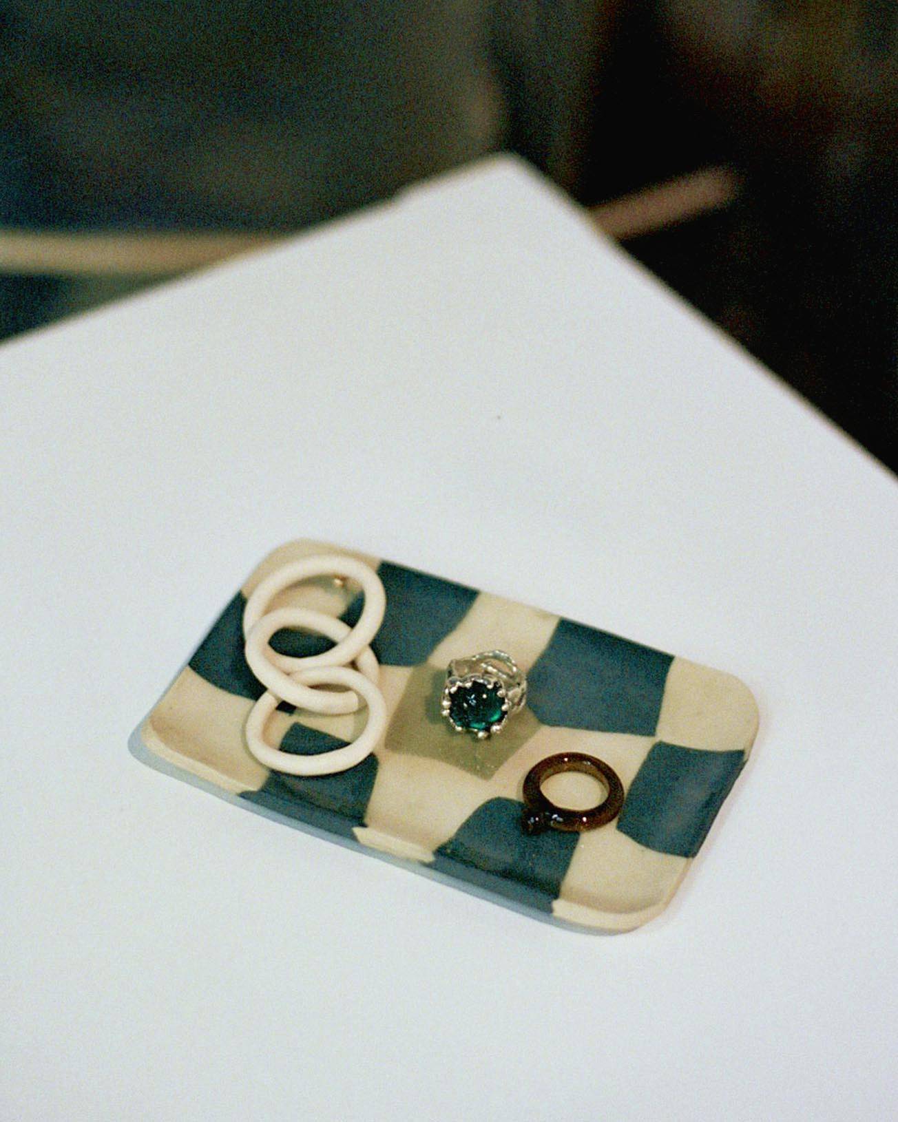 Image of three pieces of jewelry on a ceramic dish. 