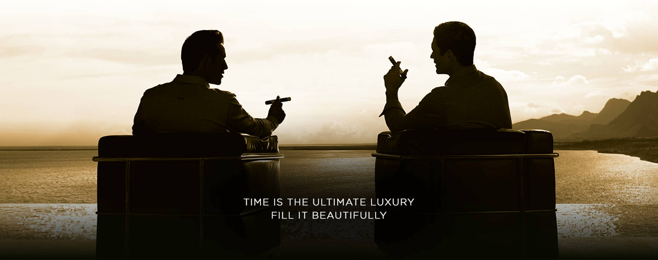 Zwei Zigarrenaficionados geniessen Ihre Davidoff Zigarren sitzend in bequemen Sofas mit Meerblick.