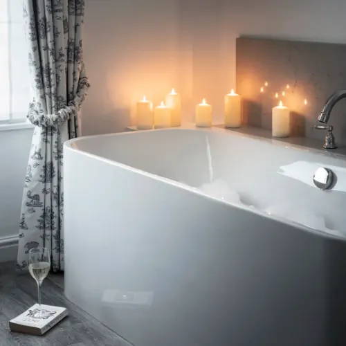 Illuminated candles placed around bubble bath 