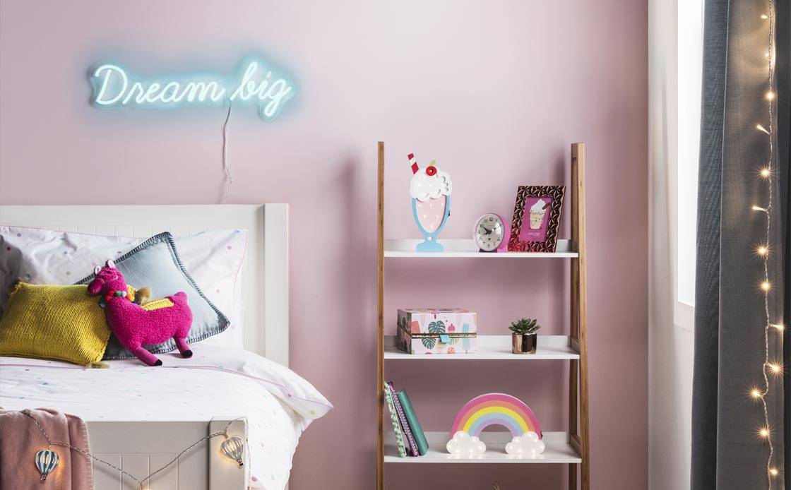 A pink room with 'dream big' neon light and sundae collection decorations.