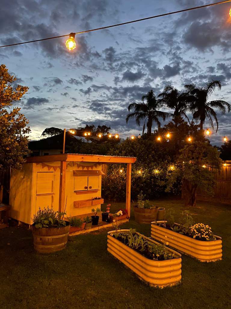 A timber cubby house in the garden lit up at night time