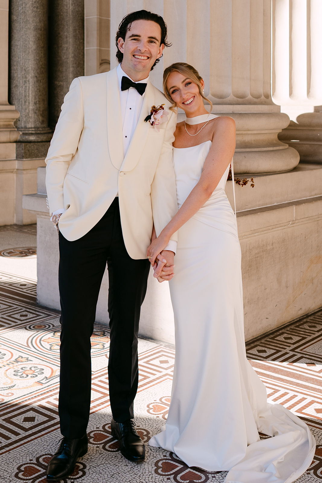 A couple in formal wedding attire smiling and holding hands.