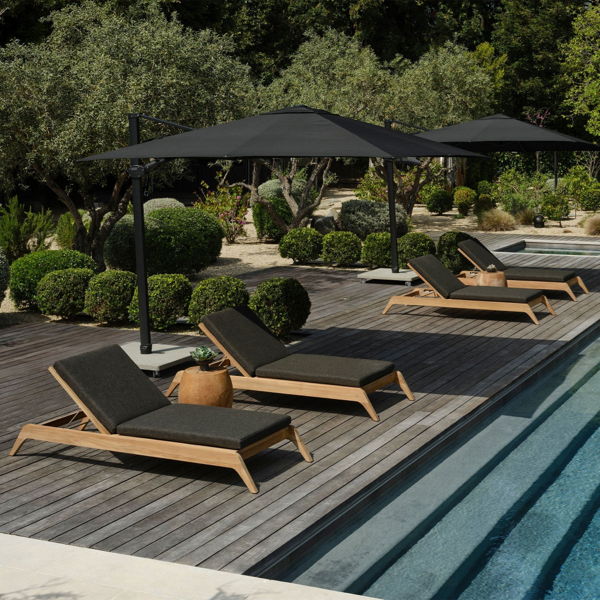 Poolside chaise lounges with umbrellas arranged in a row on a wood deck for comfortable outdoor entertaining.