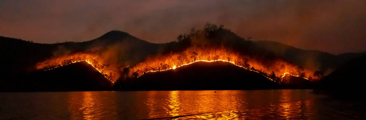 A hill on fire across a body of water