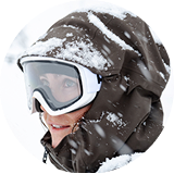 Person wearing ski goggles and a winter jacket in snowy conditions.
